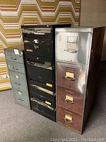 Three vintage metal file cabinets side by side, front view, showing drawers and handles
