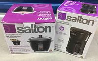 Two boxed Salton kitchen appliances side by side: a rice cooker and a coffee maker, showing brand and product images on packaging.