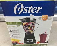 Boxed Oster blender showing brand, power of 700 watts, 8 speeds, and 6 cup glass jar capacity.