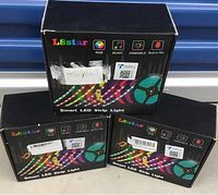 Three black retail boxes of Lesstar Smart LED Strip Light showing RGB, music, dimmable, and built-in mic features.