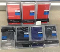 Front view of seven external USB 2.0/3.0 portable hard drives in original packaging, three in red packages and four in black/dark blue KESU packages.