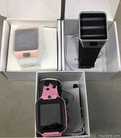 Lot with three smart watches in open boxes, all with charging cords visible.