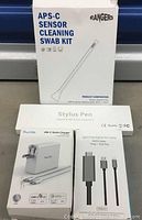 APS-C Sensor Cleaning Swab Kit, Stylus Pen box, Quntis USB-C Quick Charger, and Lightning digital AV cable boxed shown together.
