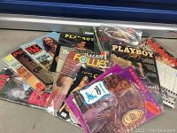 Lot of vintage adult magazines displayed in a fan arrangement, showing partial covers including Playboy, Penthouse, Follies, Bazaar, Hee Monthly, among others.
