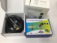 Open box showing Wi-Fi digital microscope box with colorful graphics and white box with Wi-Fi endoscope components inside.