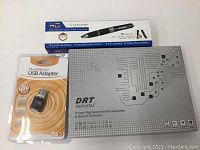 Box packaging for pen camcorder, dual band USB adapter in blister pack, and repair tool kit box with circuit pattern design.