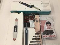Lot contents including boxes and devices: modeling comb box, blackhead remover device box, electric eyelash curler packaging, pink nylon hair cover package.