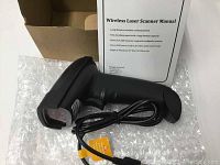 Photo of wireless laser scanner with attached USB power cord and user manual in background, showing scanner body and part of the manual text.
