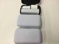 Three gray zippered carrying cases stacked with one open showing contents inside.