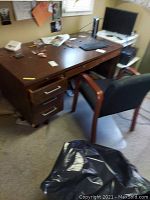 Wooden desk with drawers, cluttered top, showing signs of wear and scratches