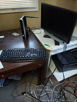Photo showing Dell monitor on desk, Canon printer on lower shelf, Staples keyboard on desk with connectivity cables visible.