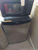 Photo of GE microwave placed on top of Danby refrigerator, showing relative size and condition.