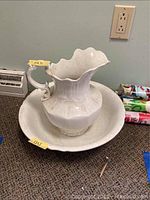 Overall view of white pitcher centered inside white bowl on carpeted floor showing shape and scale