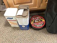 Photo of three vintage tins including Mobil oil tin, Kiwi shoe care kit tin, and Keebler saltines tin placed on carpet.