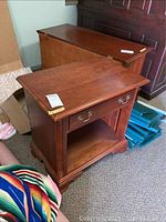 End table shown from front and side angle, revealing drawer with brass handles and open shelf below.