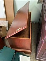 View of Lane cedar chest partially open showing wood finish exterior and metal brand tag.