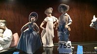 Three porcelain figures on shelf: curtsy girl, dancing girl, fisherman boy