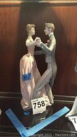 Front side view of Lladro dancing couple figurine illustrating the woman in a light pink gown and the man in gray suit.