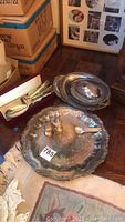 Photo showing several large silver plated serving trays and the weighted salt and pepper shakers with a small fork on a scalloped edge tray.