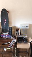 Overall shot of skateboard leaning against wall with boxes, games and tools on dresser