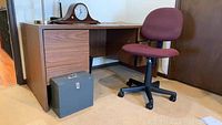 Desk, swivel chair, and metal filing box grouped in room