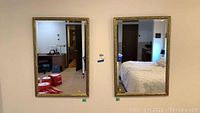 Pair of matching rectangular wall mirrors hanging side by side, reflecting the interior of rooms with visible furnishings.