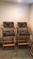 Two wooden barstool chairs with armrests and footrests, featuring race horse tapestry fabric upholstery on the seats and backs, positioned side by side.