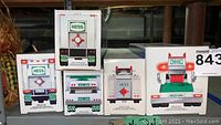 Photo of stacked original boxes showing the back side of Hess collectible trucks from 1988, 1989, 1994, 1997 years and one with a Toy Truck Bank label.