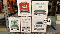 Five Hess truck boxes stacked showing rear views and branding from years 2002, 2003, 2004, 2005, and 2008.