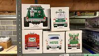 Boxes of five Hess trucks stacked on a shelf showing rear perspectives and year labels