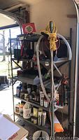 Photo of shelving unit with various automobile care sprays, tools, jumper cables, and other items