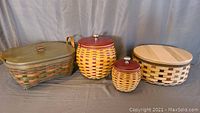 Four woven Longaberger baskets in various sizes with lids and covers displayed on cloth background