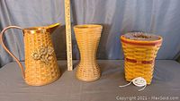 Photo showing all three Longaberger vase baskets with measuring scale; pitcher basket with copper handle and rim, plain vase basket, and snapdragon lined basket.