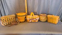 Full set of five Longaberger lidded baskets in various styles and sizes, displayed with a yardstick reference to size.