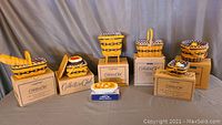 Display of seven Longaberger miniature baskets with fabric liners and miniature food accessories, placed on top of original boxes.