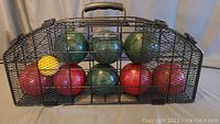 Full set of bocce balls in green and red with a yellow pallino in a black metal carrying case with a handle.