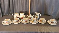 Full tea service set shown with six cups, six saucers, small teapot, and three small pitchers, all decorated in Pomona fruit pattern.