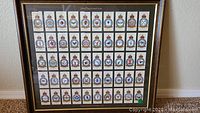 Full view of the framed set showing all 50 Royal Air Force badges cigarette cards arranged in a grid under glass with a wood frame.