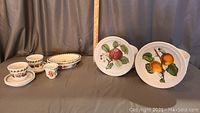 Sandwich plates and soup bowls with visible fruit designs along with miniature flower pots, candle holder, and oblong bowls.