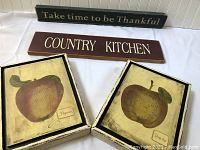 Lot of 4 inspirational home signage and wall art pieces including two text-based wooden signs and two framed apple prints.