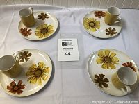 Full display of the lot showing 4 luncheon plates each with a matching mug on plain white cloth background