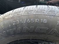 Close up of tire sidewall showing size 235/65 R18 and brand Continental.