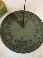 Close-up of solid metal sundial showing numbers and wording 'I COUNT ONLY SUNNY HOURS'