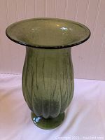Front side view of large green glass vase, showing bulbous rippled body and flared rim