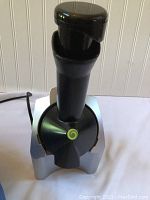 Front view of Yonanas Classic Original soft serve maker showing black cylindrical chute and silver base with logo.