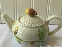 Side view of Belleek teapot showing spout, handle, and acorn top lid detail