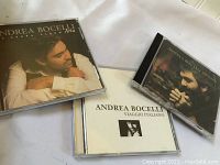 Three Andrea Bocelli CDs: Aria - The Opera Album, Romanza, and Viaggio Italiano arranged on a white surface.
