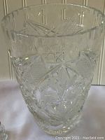 Clear leaded glass vase with intricate cut patterns, geometric and floral motifs visible.