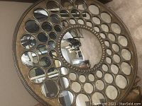 Full view of the large round metal frame mirror with central and surrounding small round mirrors.