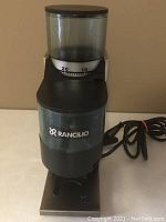 Front view showing the clear bean hopper, grind adjustment dial, Rancilio logo, and dosing container with lever.